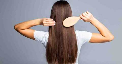 Rear view of Combing healthy long straight female hair isolated on gray background