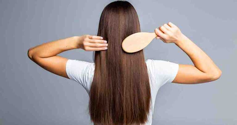 Rear view of Combing healthy long straight female hair isolated on gray background