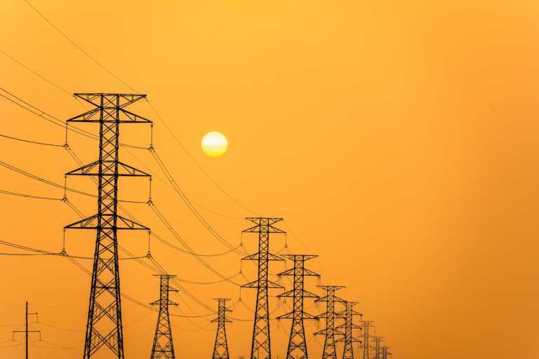 electricity-pillars-against-a-colorful-yellow-sunset-silhouette-high-voltage-electric-towers-power-lines-photo