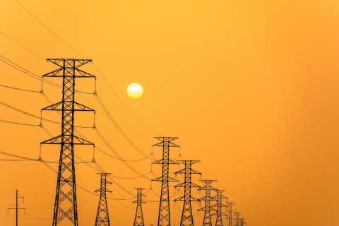 electricity-pillars-against-a-colorful-yellow-sunset-silhouette-high-voltage-electric-towers-power-lines-photo