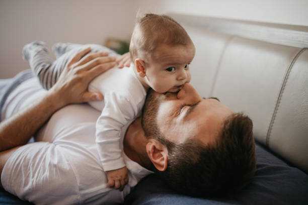 Father playing in bed with his little baby boy