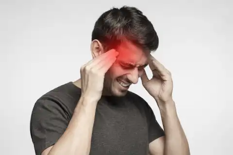 Closeup of young man touching temples with fingers as if suffering from severe migraine, feeling sick, isolated on gray background